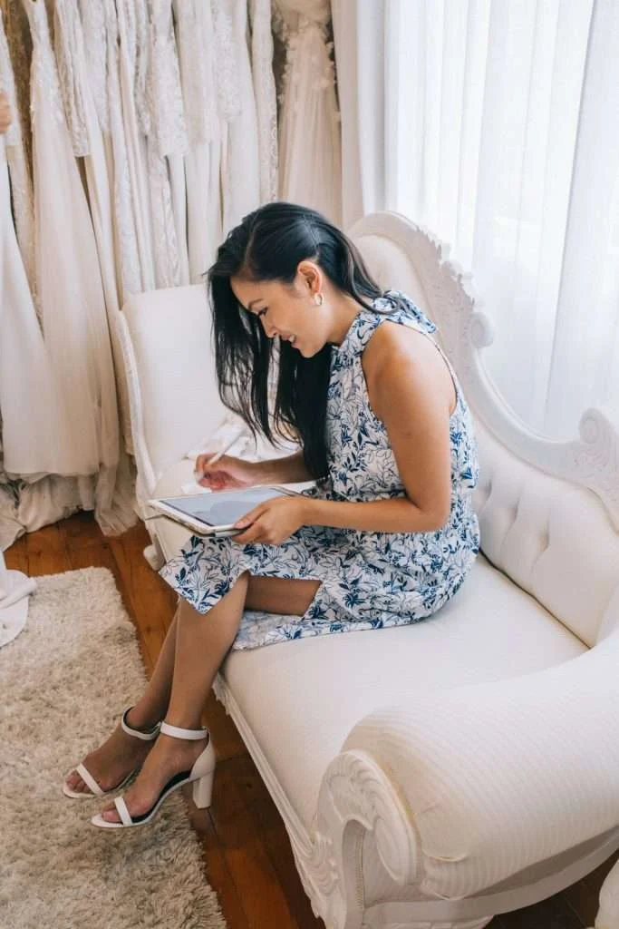 Bride sitting on a sofa lacing her shoes in a Trish Peng gown