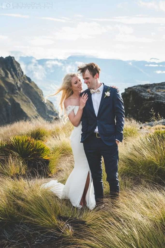 Bride and groom on a windswept New Zealand hillside, bride in a Trish Peng gown